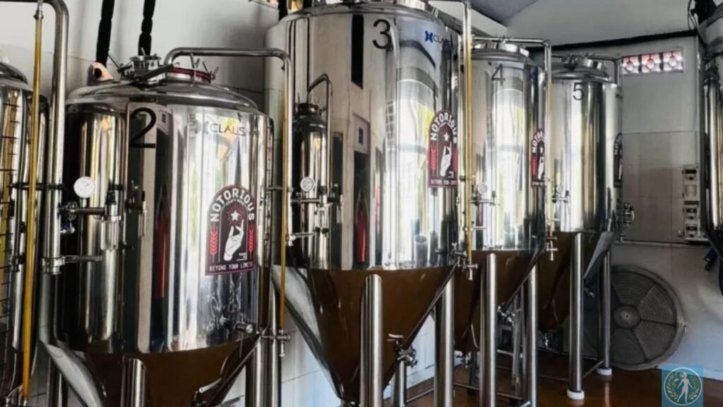 Guia da Cerveja Artesanal: Onde o Sabor Encontra o Bem-Estar e o Turismo 4 foto em alta definição da fachada ou do interior de uma tap house moderna em Itajaí, com iluminação quente e tanques de inox ao fundo, para reforçar o aspecto de "lugar de excelência".